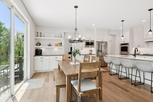 dining area with light wood finished floors, an inviting chandelier, and recessed lighting