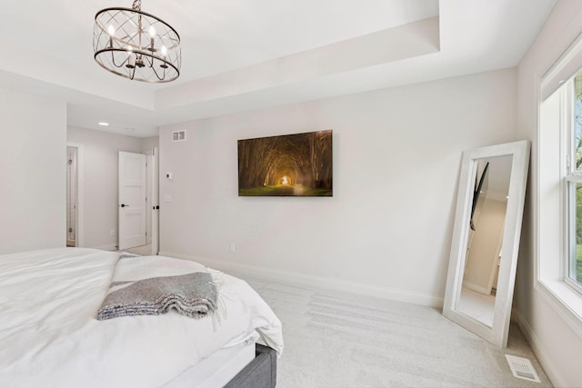 bedroom featuring baseboards, visible vents, light carpet, a raised ceiling, and a notable chandelier