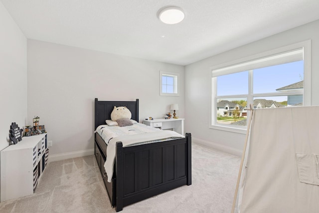 bedroom with baseboards and light colored carpet