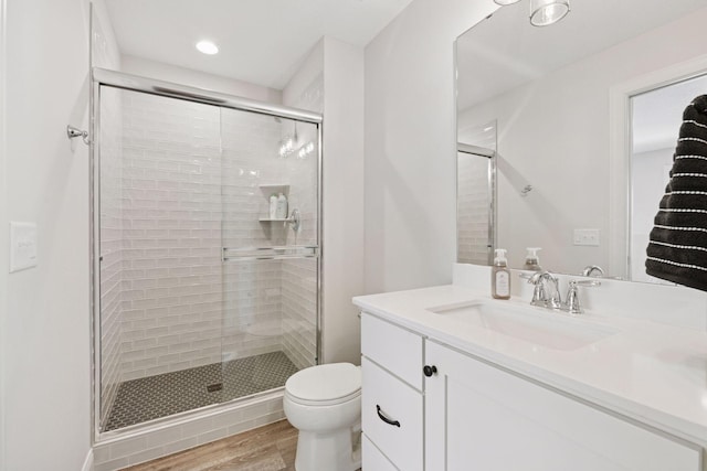 full bath featuring toilet, wood finished floors, vanity, recessed lighting, and a stall shower