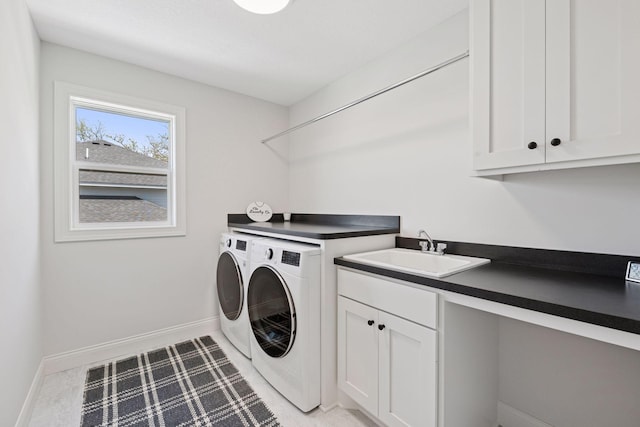 laundry area with cabinet space, washing machine and dryer, baseboards, and a sink