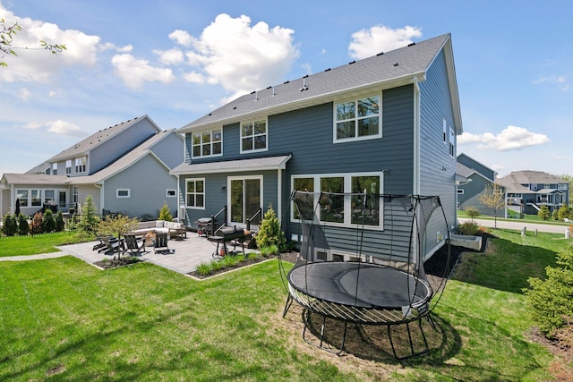 rear view of house with an outdoor living space with a fire pit, a trampoline, a patio, and a lawn