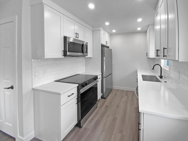 11601 Wren St NW, Coon Rapids, MN 55433 - kitchen with appliances with stainless steel finishes, a sink, light countertops, baseboards, and light wood finished floors
