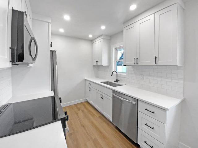 11601 Wren St NW, Coon Rapids, MN 55433 - kitchen with appliances with stainless steel finishes, a sink, light wood finished floors, white cabinets, and recessed lighting