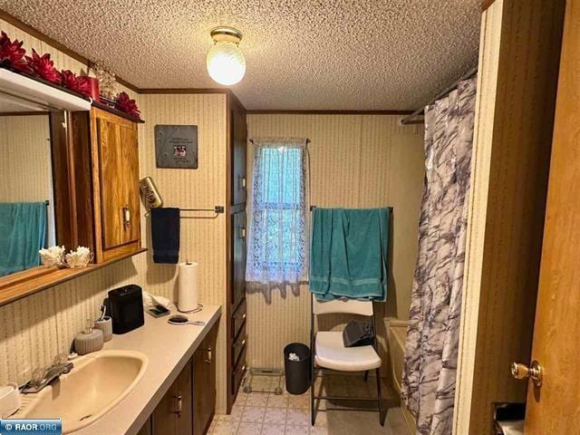 full bath with shower / bath combination with curtain, vanity, a textured ceiling, and wallpapered walls