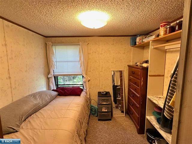 carpeted bedroom featuring a textured ceiling and crown molding