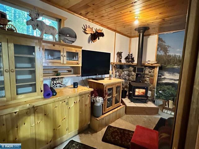 living room with light tile patterned flooring, a wood stove, and wood ceiling