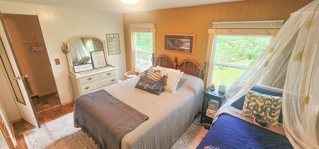 30280 County Highway 26, Holmesville Twp, MN 56501 - bedroom featuring wooden walls, wood finished floors, and multiple windows