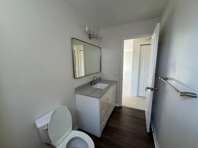 bathroom with baseboards, wood finished floors, toilet, and vanity