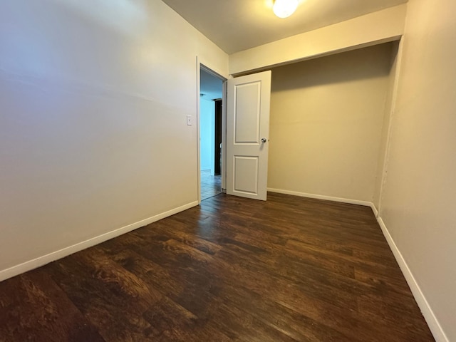 spare room with baseboards and dark wood-style floors