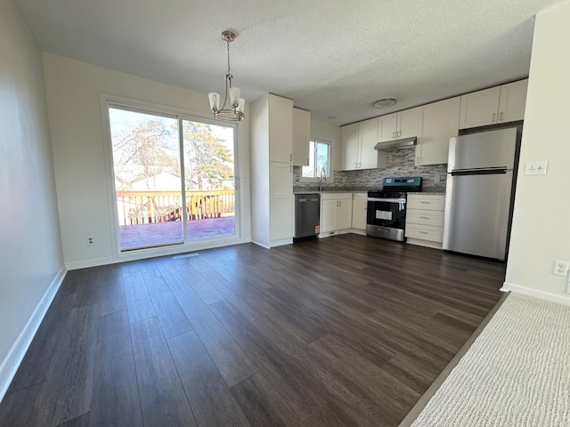 kitchen with an inviting chandelier, under cabinet range hood, stainless steel appliances, and baseboards