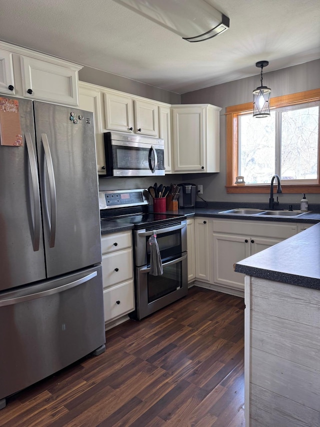 601 Maplewood Dr SE, Pelican Rapids, MN 56572 - kitchen featuring appliances with stainless steel finishes, a sink, dark wood finished floors, dark countertops, and white cabinetry