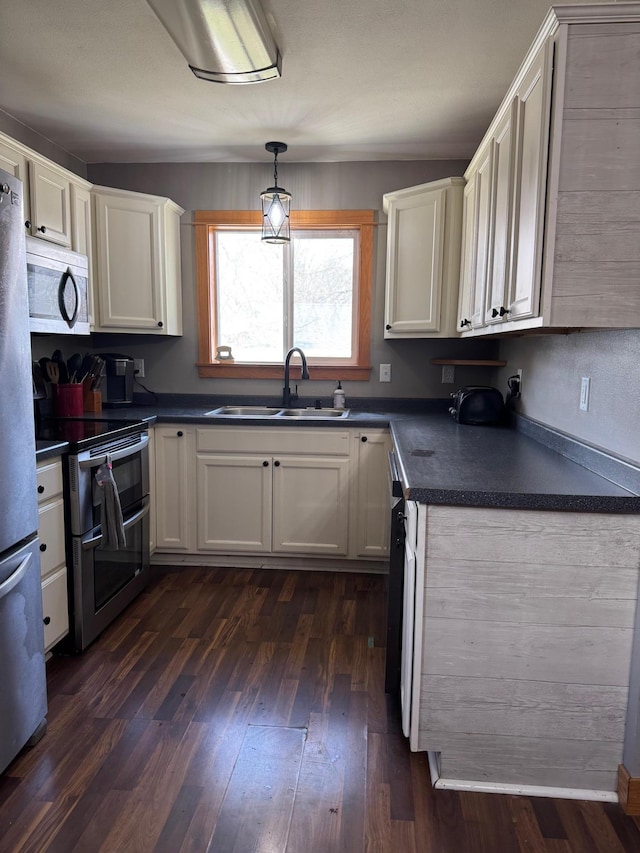 601 Maplewood Dr SE, Pelican Rapids, MN 56572 - kitchen featuring a sink, appliances with stainless steel finishes, dark countertops, white cabinets, and dark wood finished floors