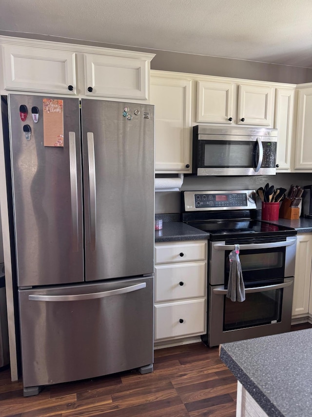 601 Maplewood Dr SE, Pelican Rapids, MN 56572 - kitchen featuring stainless steel appliances, dark countertops, dark wood-type flooring, and white cabinetry