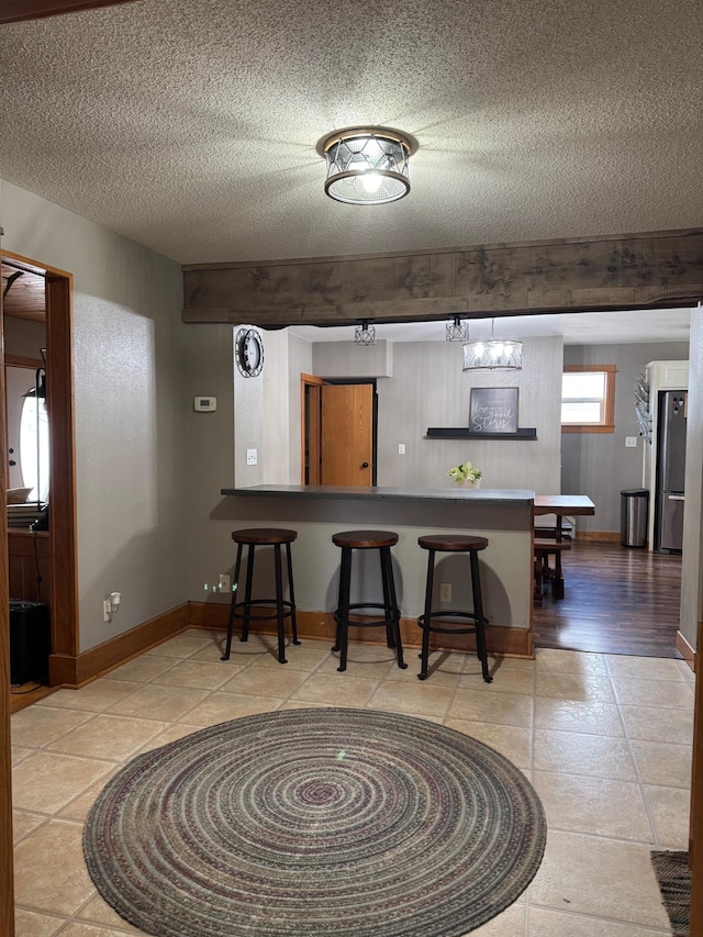601 Maplewood Dr SE, Pelican Rapids, MN 56572 - kitchen with a kitchen breakfast bar, freestanding refrigerator, baseboards, and a textured ceiling