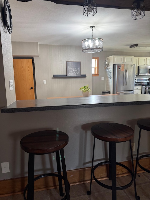601 Maplewood Dr SE, Pelican Rapids, MN 56572 - kitchen with appliances with stainless steel finishes, white cabinetry, a kitchen bar, and dark countertops