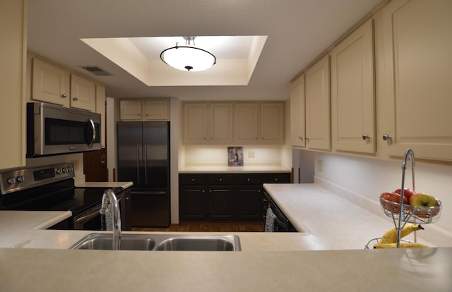 kitchen with a sink, stainless steel appliances, light countertops, visible vents, and a raised ceiling