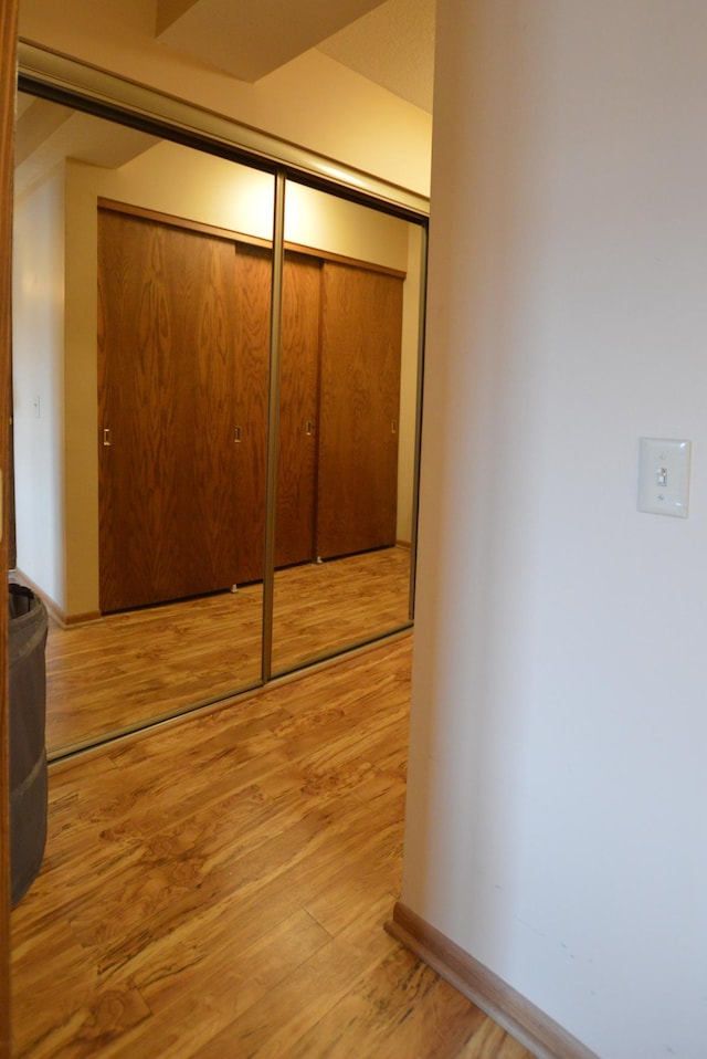 unfurnished bedroom featuring light wood finished floors, baseboards, and a closet