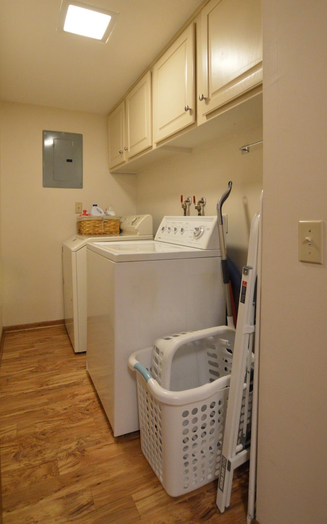clothes washing area featuring cabinet space, light wood-type flooring, electric panel, and separate washer and dryer