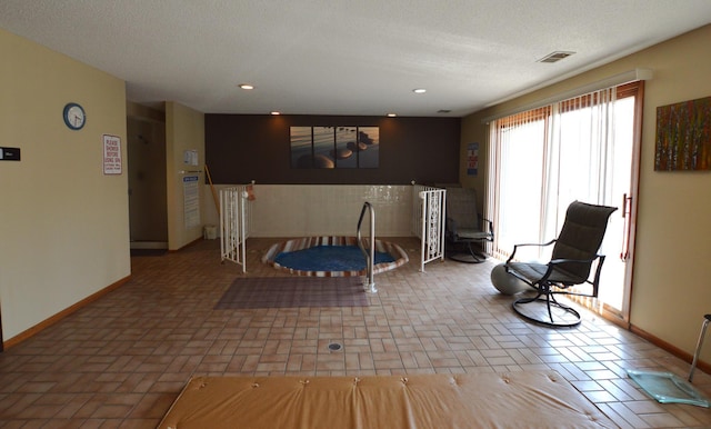 interior space with visible vents, brick floor, baseboards, and a textured ceiling