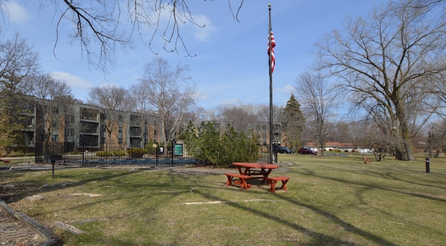 view of home's community with a lawn and fence