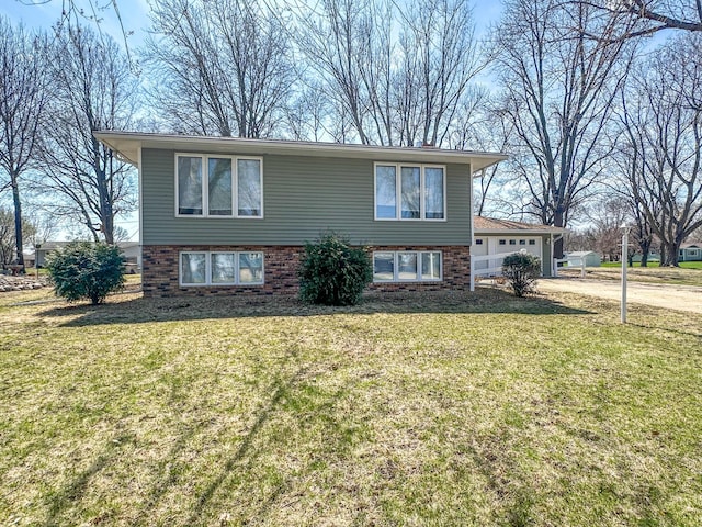split foyer home featuring driveway, brick siding, a front yard, and a garage