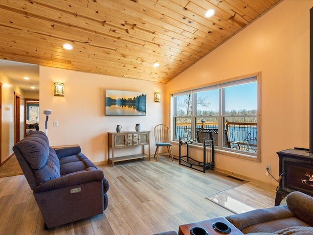 living room featuring lofted ceiling, wooden ceiling, light wood-style flooring, and a wood stove