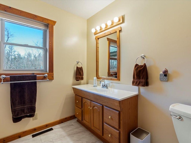 bathroom featuring vanity, baseboards, toilet, and visible vents