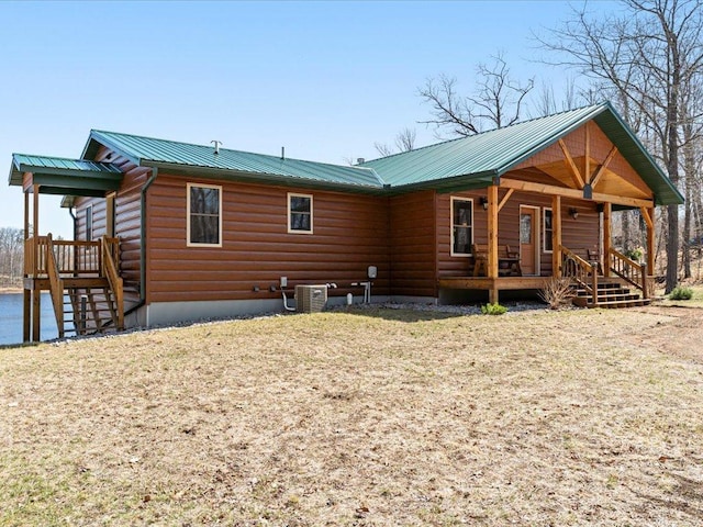 back of house with metal roof, cooling unit, faux log siding, and covered porch