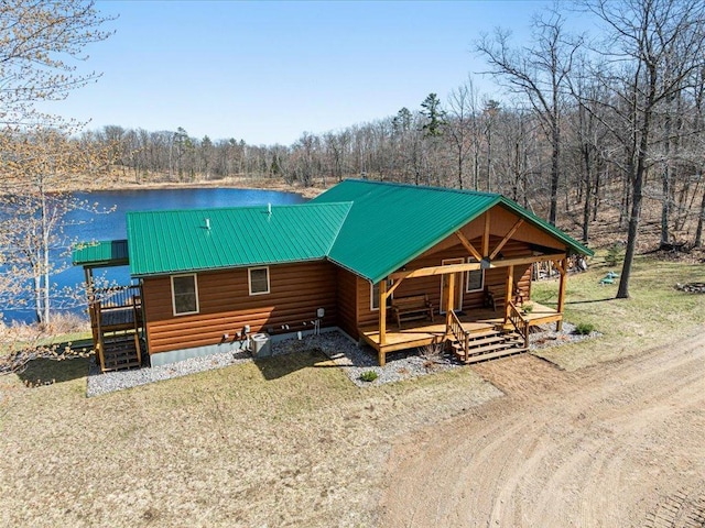 cabin with covered porch, log exterior, metal roof, stairway, and a forest view