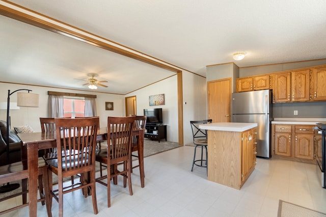 kitchen featuring freestanding refrigerator, a breakfast bar, a kitchen island, light countertops, and ceiling fan