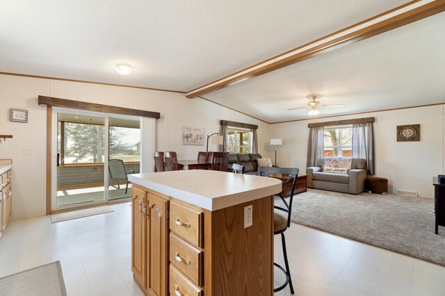 kitchen with a kitchen breakfast bar, vaulted ceiling with beams, a kitchen island, open floor plan, and light floors