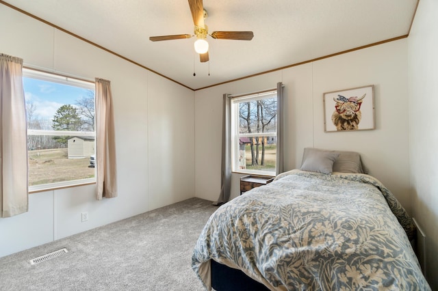 carpeted bedroom featuring crown molding, visible vents, ceiling fan, and lofted ceiling