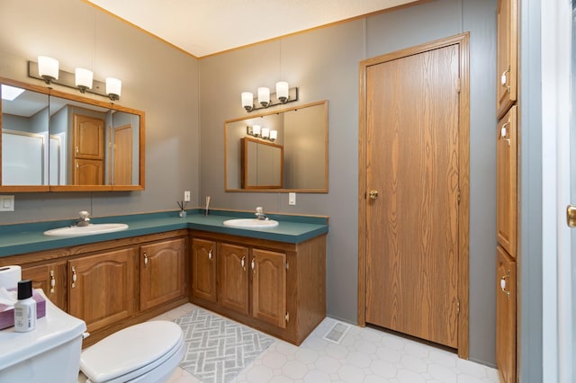 full bathroom with toilet, double vanity, a sink, and tile patterned floors