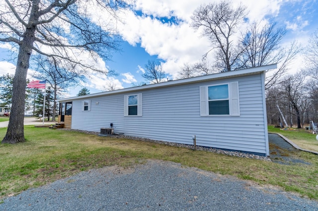 view of side of home featuring central AC and a yard