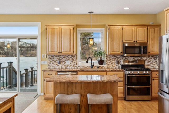 5320 132nd St W, Apple Valley, MN 55124 - kitchen with light wood finished floors, a sink, stainless steel appliances, light stone counters, and a kitchen island