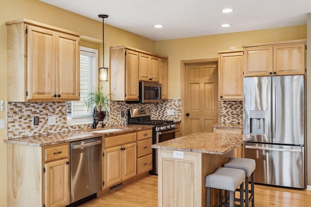 5320 132nd St W, Apple Valley, MN 55124 - kitchen featuring light wood finished floors, light brown cabinets, light stone counters, a kitchen island, and appliances with stainless steel finishes