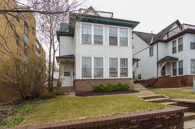 view of front of home with a chimney, brick siding, a front yard, and stucco siding