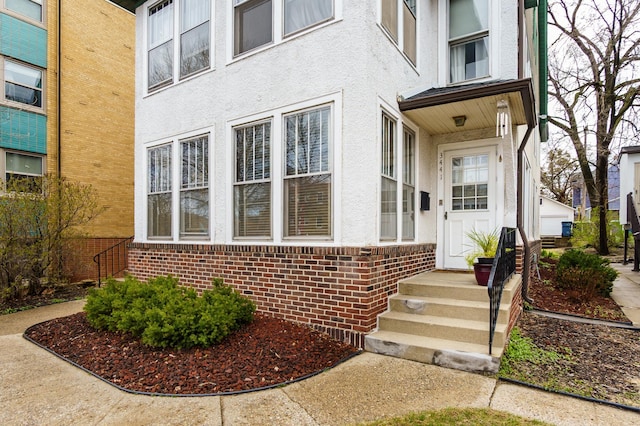 view of exterior entry with brick siding and stucco siding