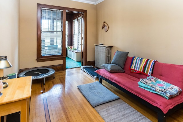 living area with crown molding, radiator heating unit, and wood finished floors