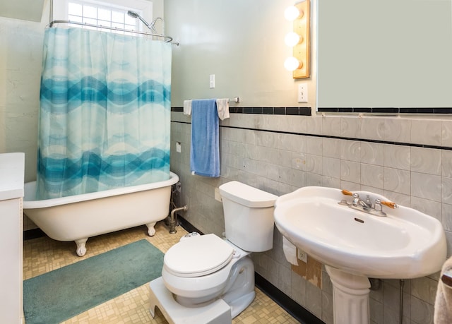 full bathroom with toilet, a wainscoted wall, and tile walls