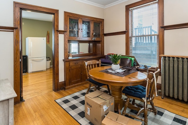 dining area with radiator, light wood-style flooring, and crown molding