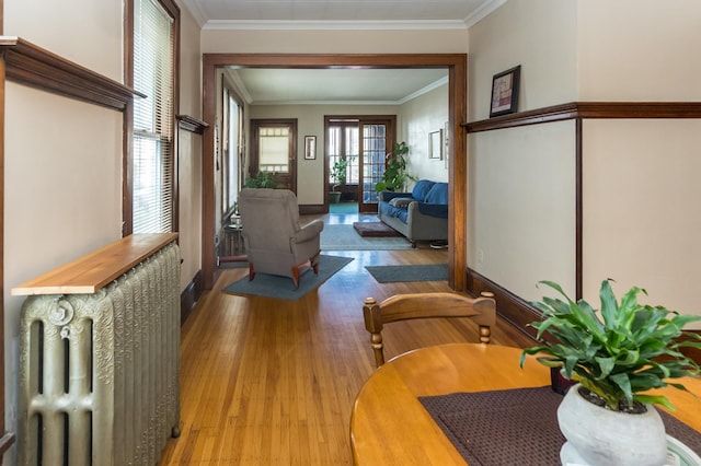 corridor with wood finished floors, crown molding, and baseboards