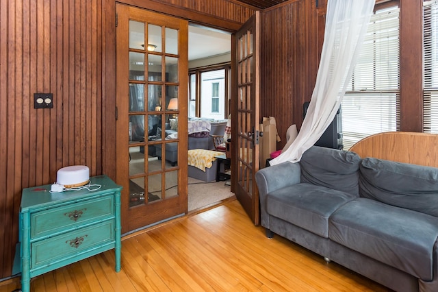 sitting room featuring wooden walls, wood finished floors, and french doors