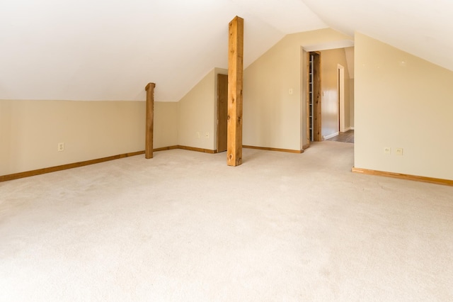 additional living space featuring light colored carpet, vaulted ceiling, and baseboards