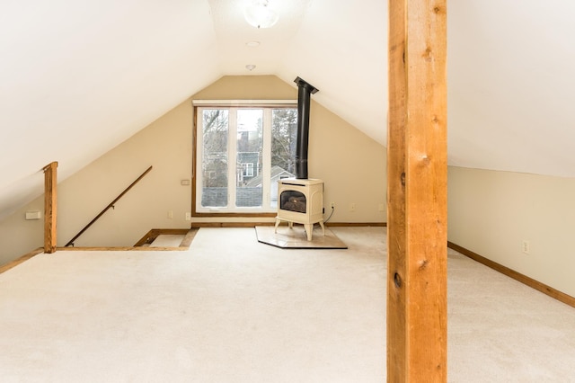 additional living space with vaulted ceiling, carpet, and a wood stove