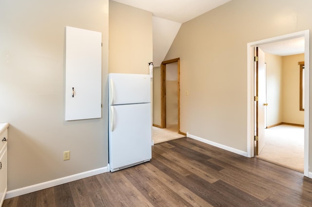 kitchen featuring baseboards, wood finished floors, and freestanding refrigerator