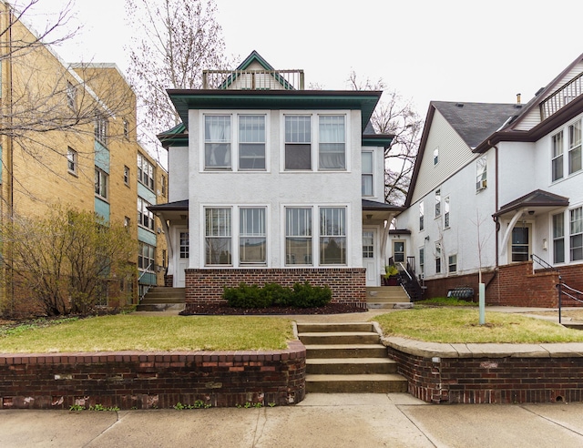 traditional style home featuring brick siding, a front yard, and stucco siding