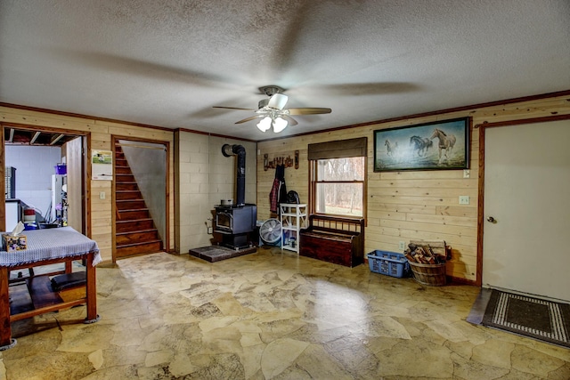 6775 State 87 SW, Backus, MN 56435 - interior space featuring wooden walls, ceiling fan, stone finish flooring, and a wood stove