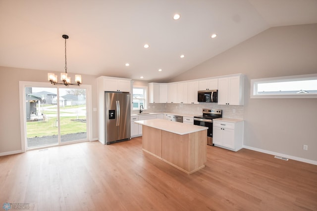kitchen with a sink, backsplash, light countertops, a notable chandelier, and appliances with stainless steel finishes